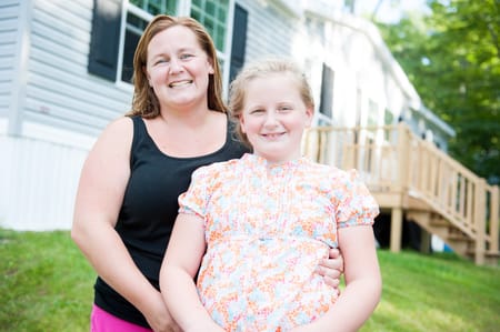 Mother and daughter in front of their home